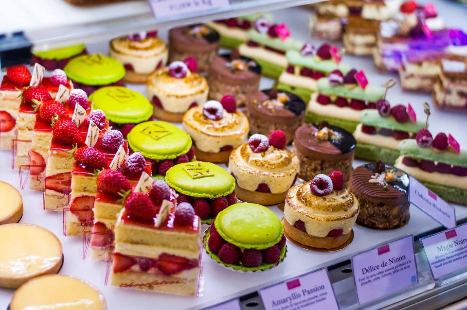 Vitrine de pâtisserie française avec assortiment de gâteaux individuels disposés sur présentoirs réfrigérés