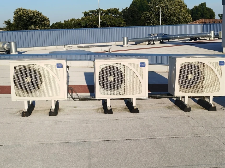 Toiture-terrasse avec trois unités extérieures de climatisation split system installées en rangée, montées sur supports anti-vibratoires