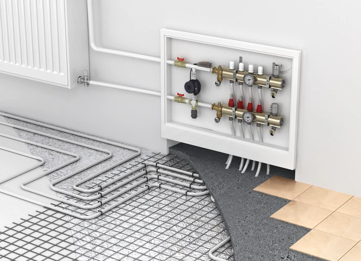 Local technique moderne avec chaudière cylindrique grise, réseau de canalisations blanches avec vannes de régulation, collecteur de distribution, vase d'expansion bleu